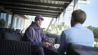 Der Ex-Tennisspieler Dominic Thiem mit Kappe und grauem Kapuzenpullover im Gespräch mit einem Journalisten.
