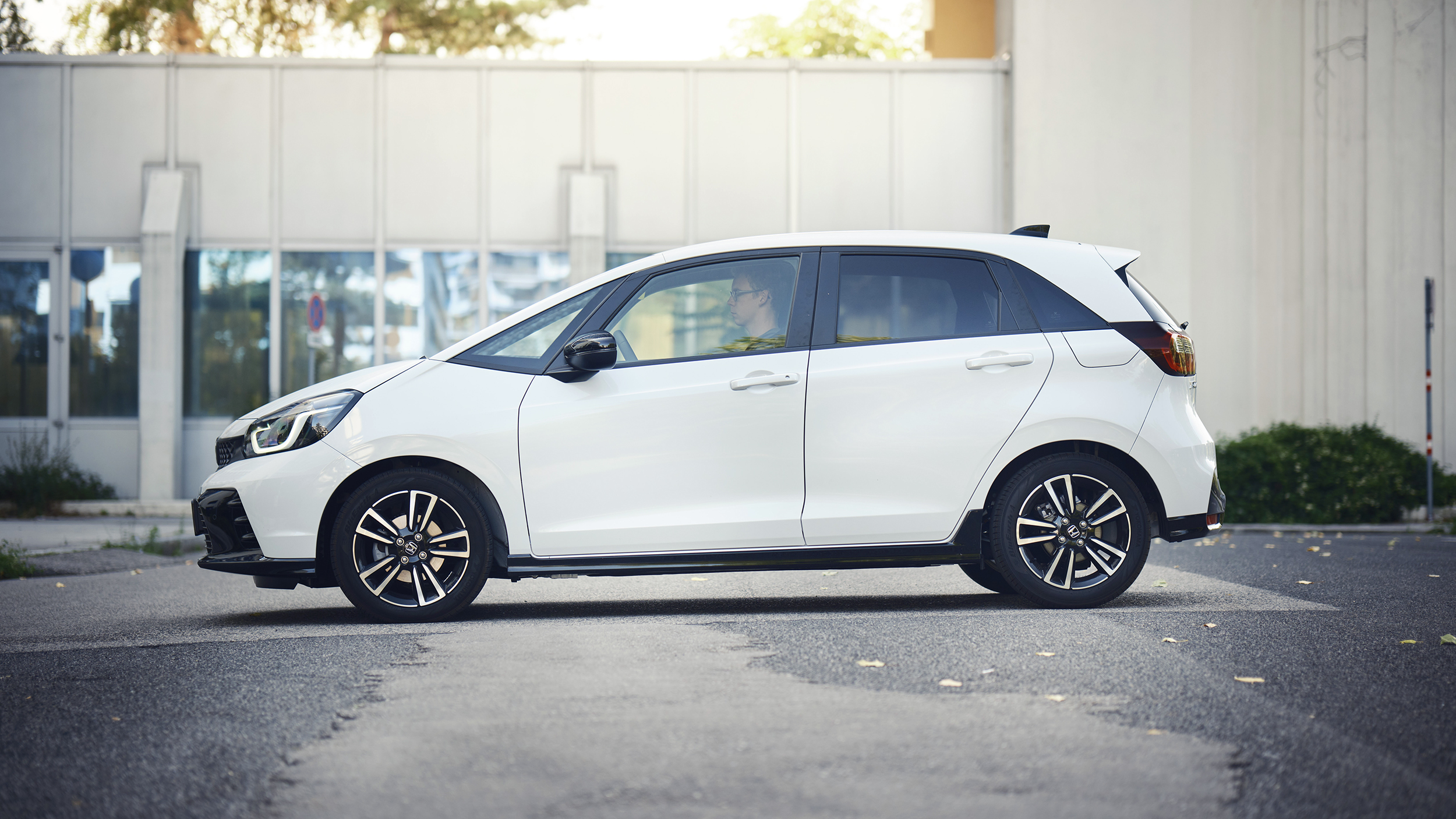 Ein weißer Honda Jazz seitlich vor einem Haus