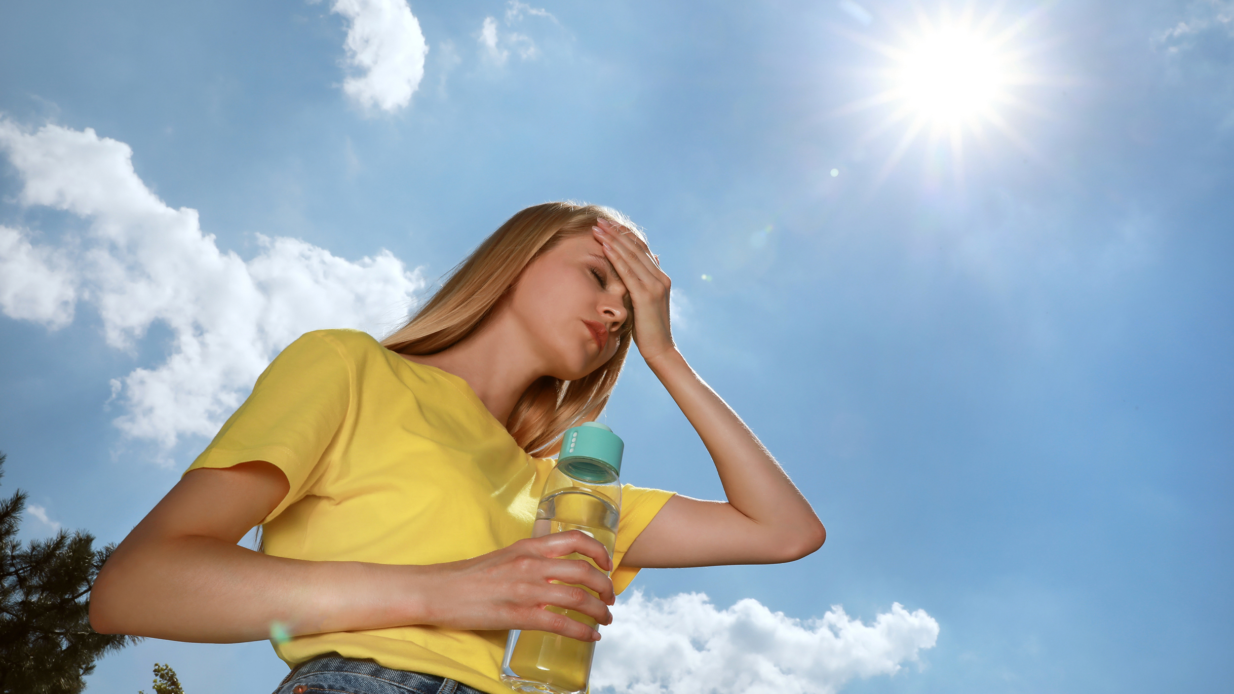 Frau mit Wasserflasche, die im Freien an einem Hitzeschlag leidet.