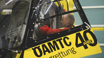 Flugretter Markus Amon lädt etwas in den Hubschrauber ein. Er ist durch die Tür von der Seite zu sehen.