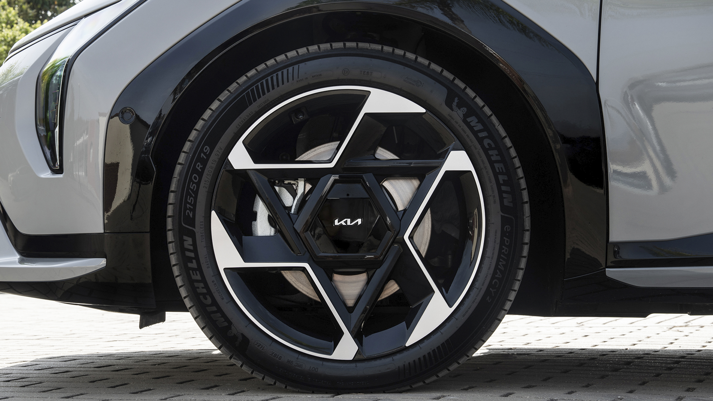 Schwarz-silberne Felgen eines grauen Autos der Marke Kia.