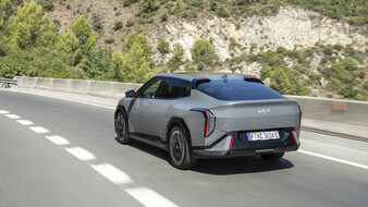 Ein graue Kia EV4-Limousine fährt über eine Landstraße.
