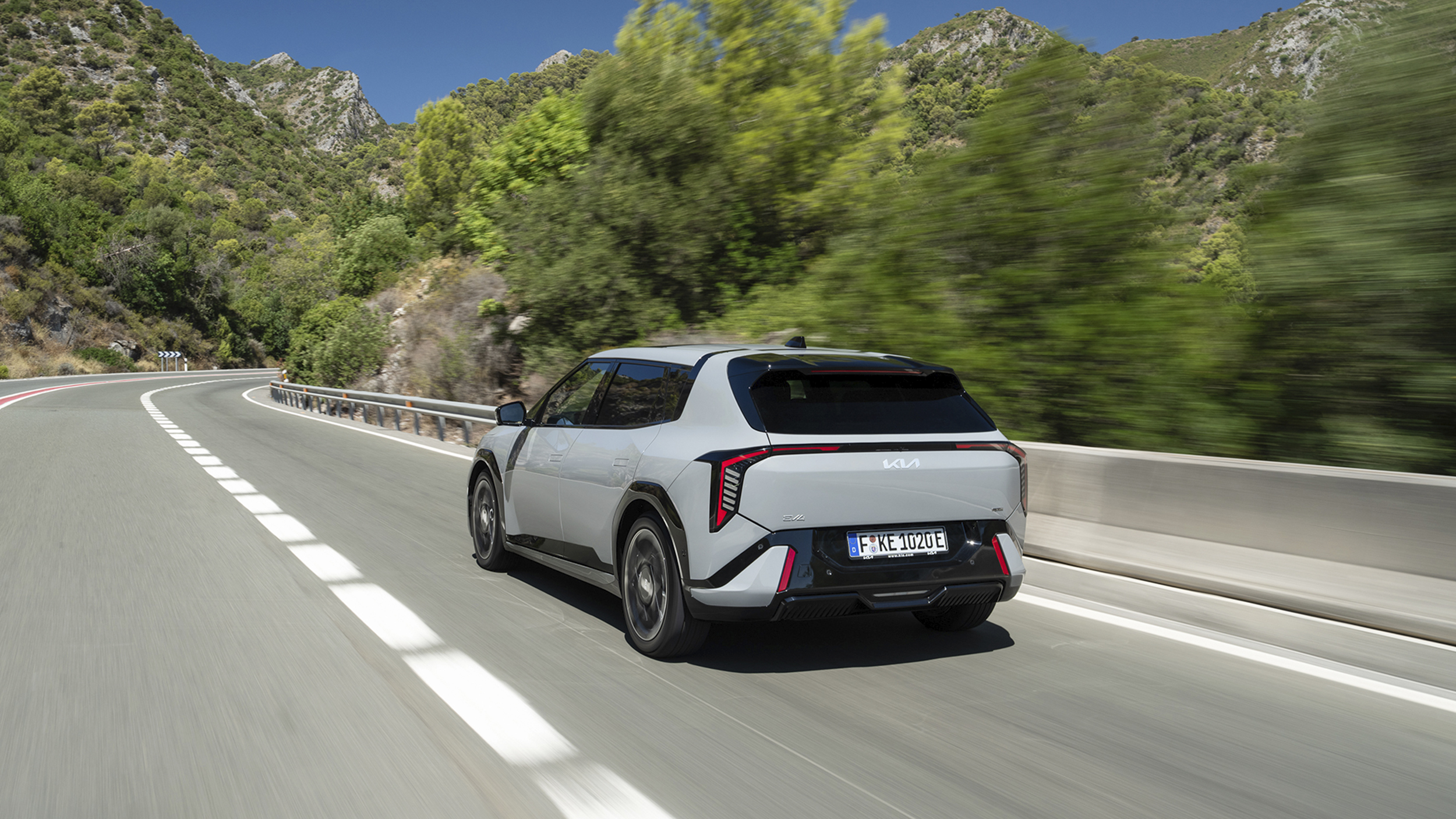 Ein grauer Kia EV4 fährt über eine Landstraße.