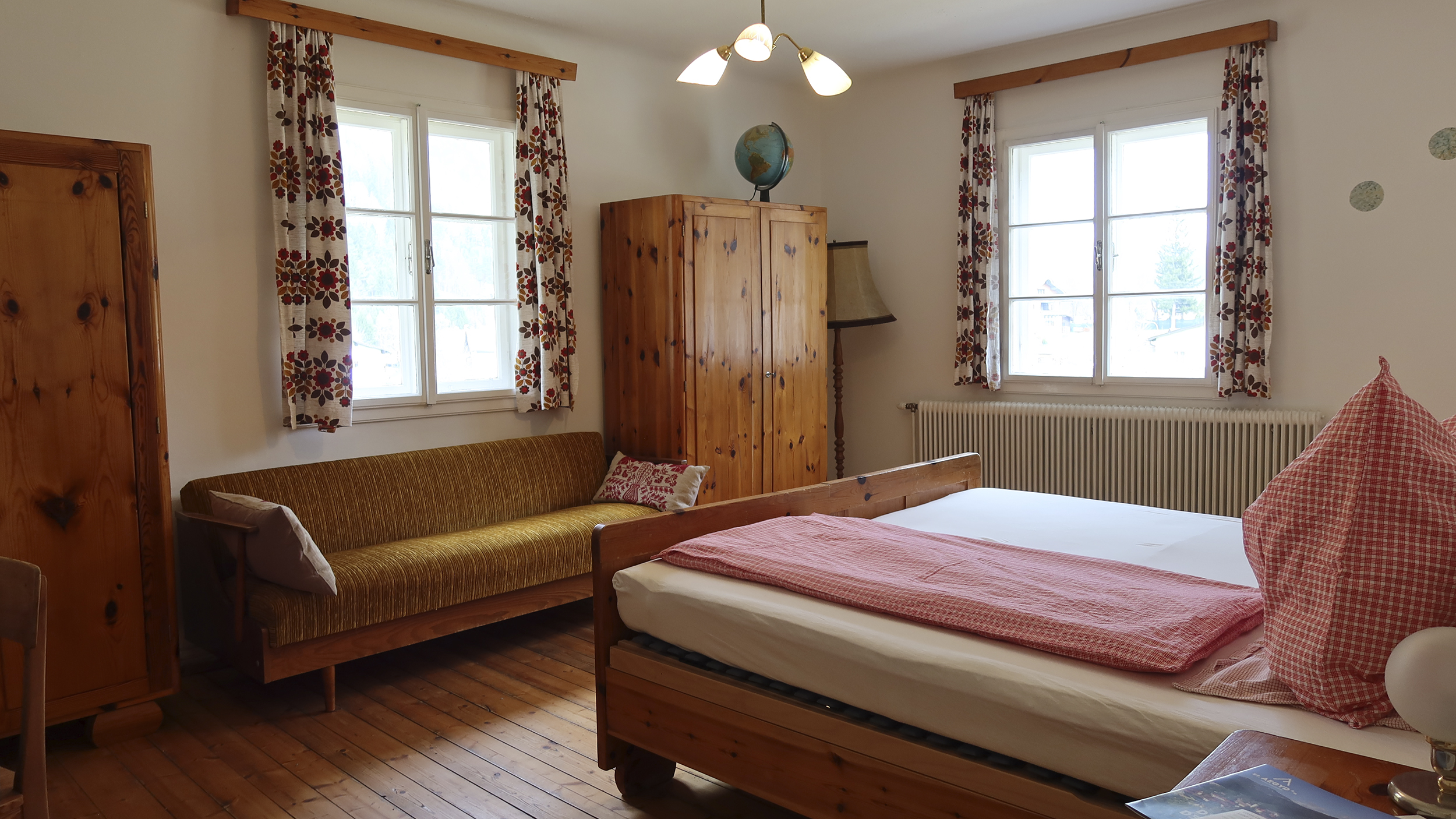 Gästezimmer im Auszeithof mit Bett, Kästen und Bank.
