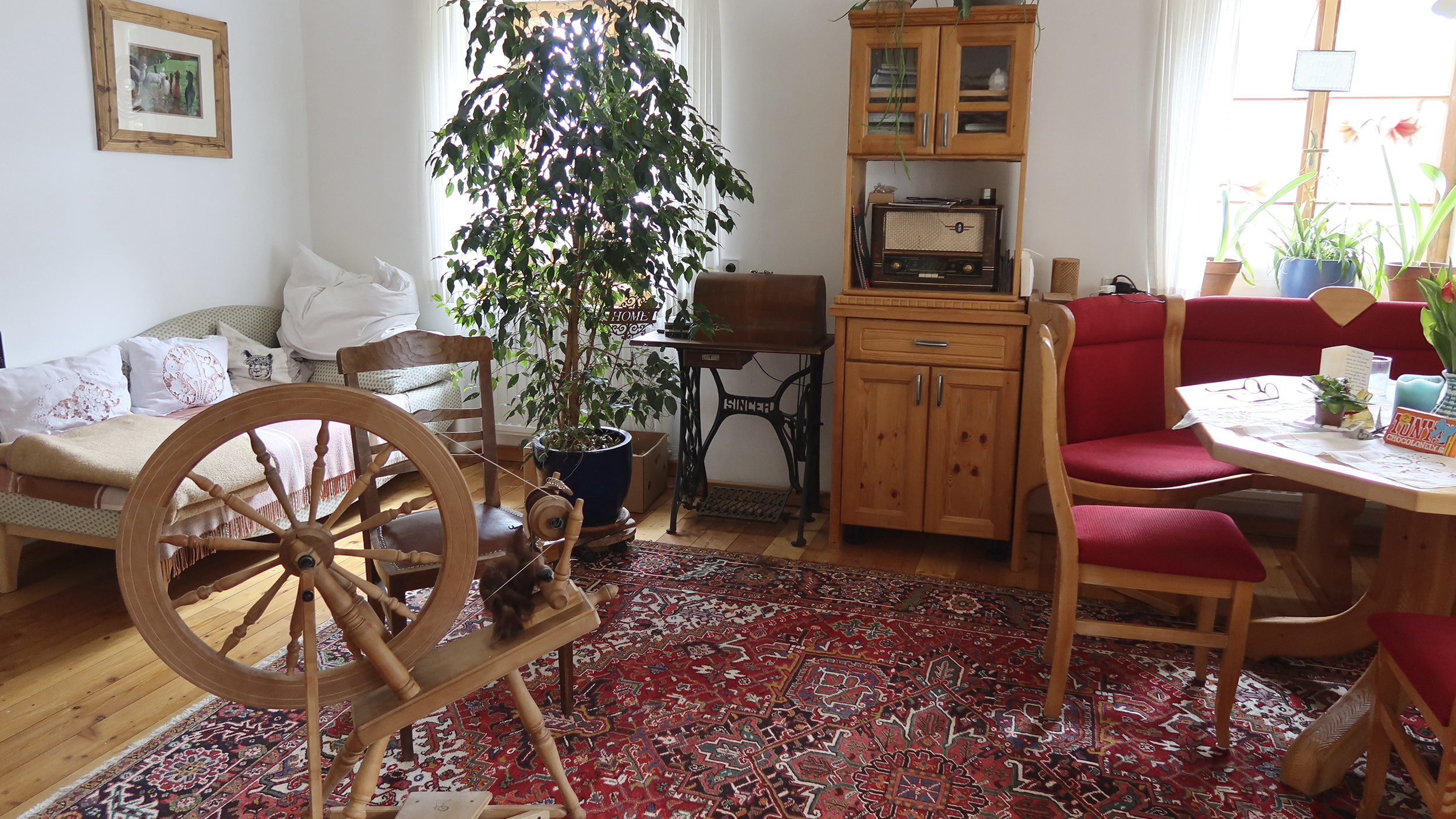 Wohnzimmer im Auszeithof mit Spindel, altem Radio und Esstisch.