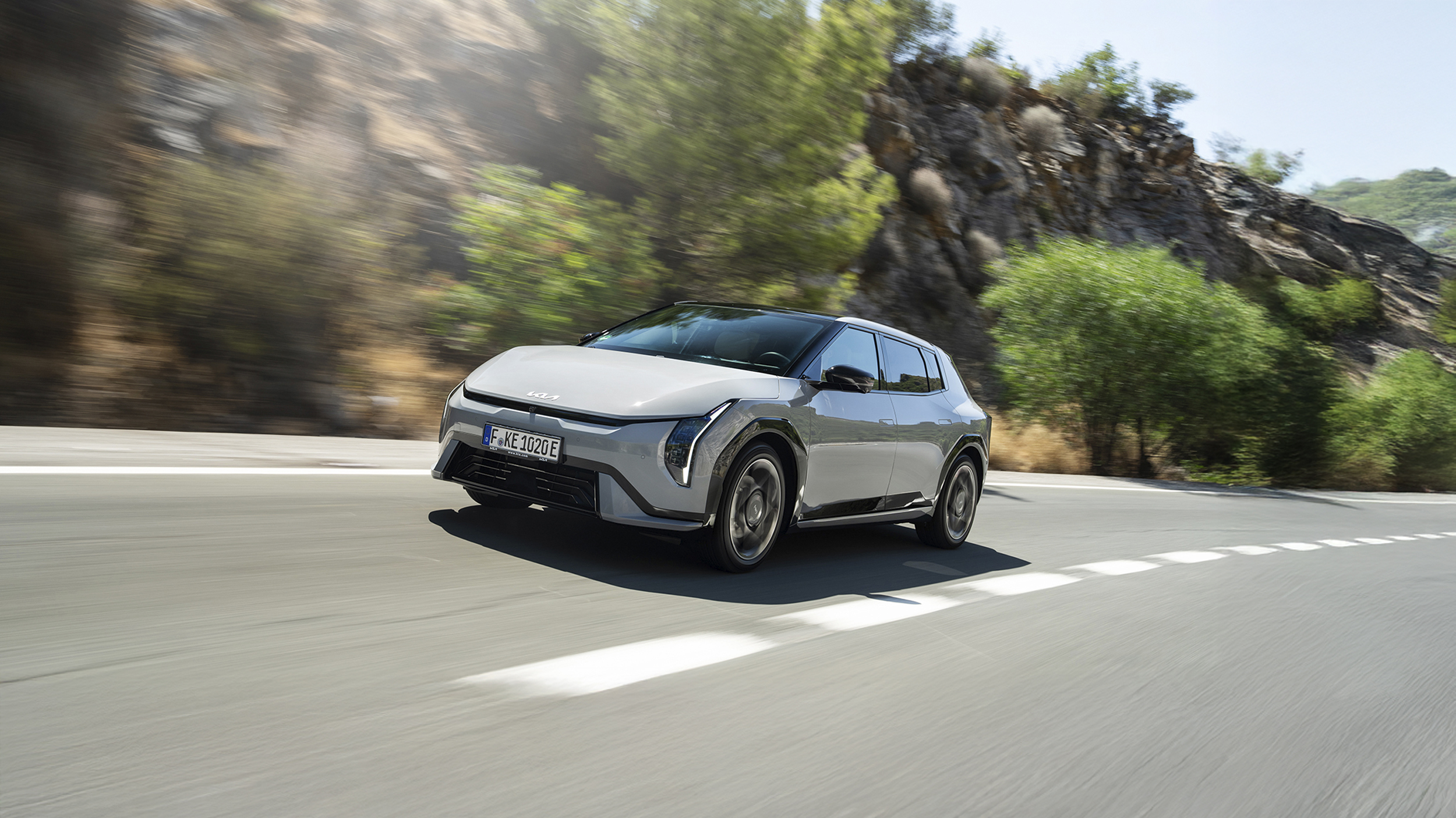 Ein grauer Kia EV4 fährt auf einer Landstraße.