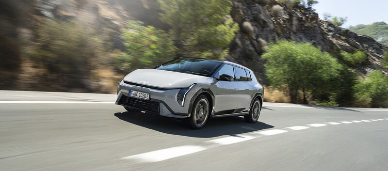 Ein grauer Kia EV4 fährt auf einer Landstraße.