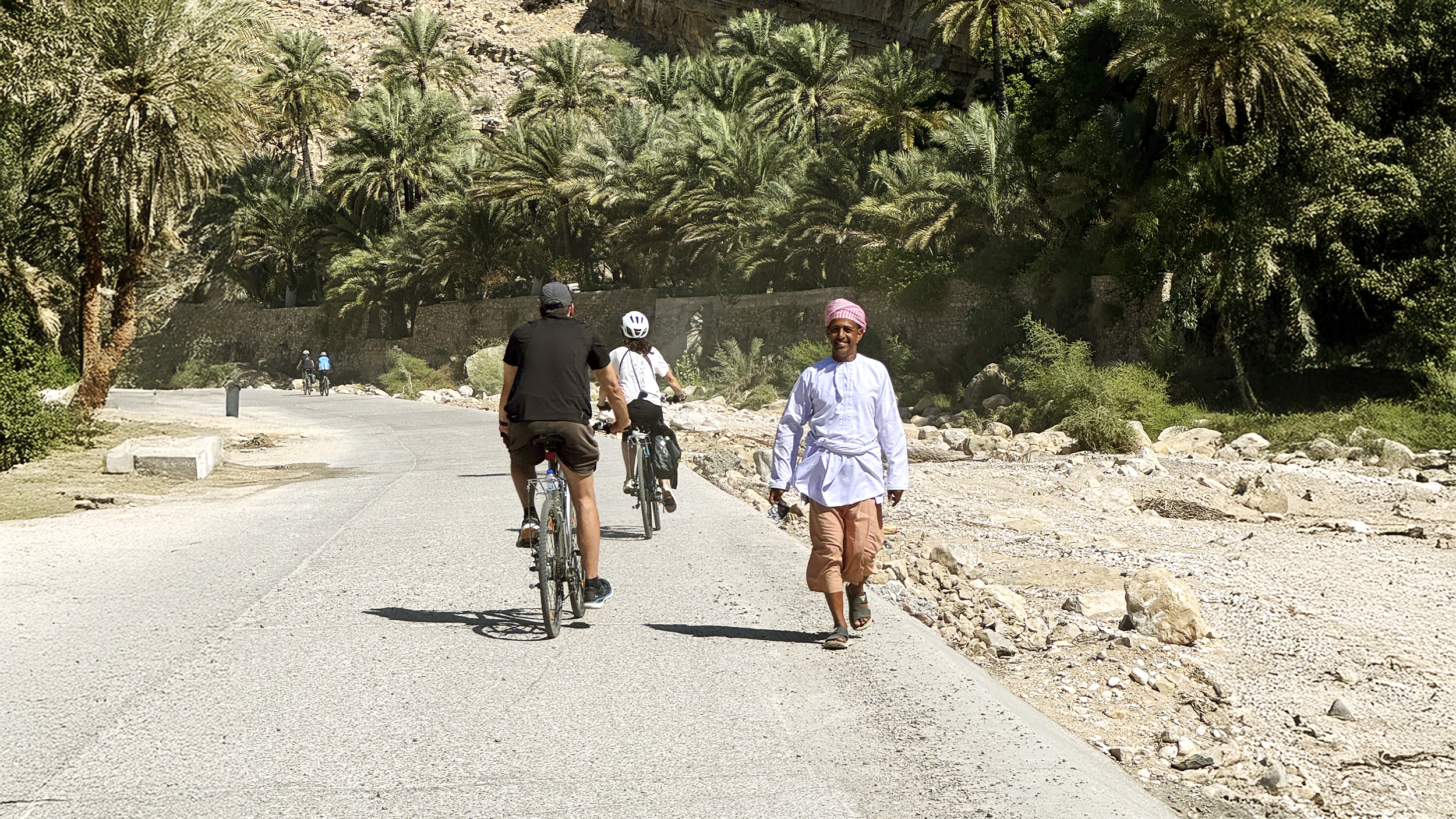 Zwei Radfahrer fahren einem Einheimischen im Oman entgegen.