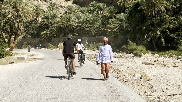 Zwei Radfahrer fahren einem Einheimischen im Oman entgegen.