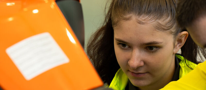 Auf dem Bild sieht man die Gesichter eines jungen Mannes und einer jungen Frau die konzentriert auf eine orangefarbene Fläche schauen