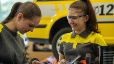 Zwei junge Frauen unterhalten sich vor einem ÖAMTC-Fahrzeug.