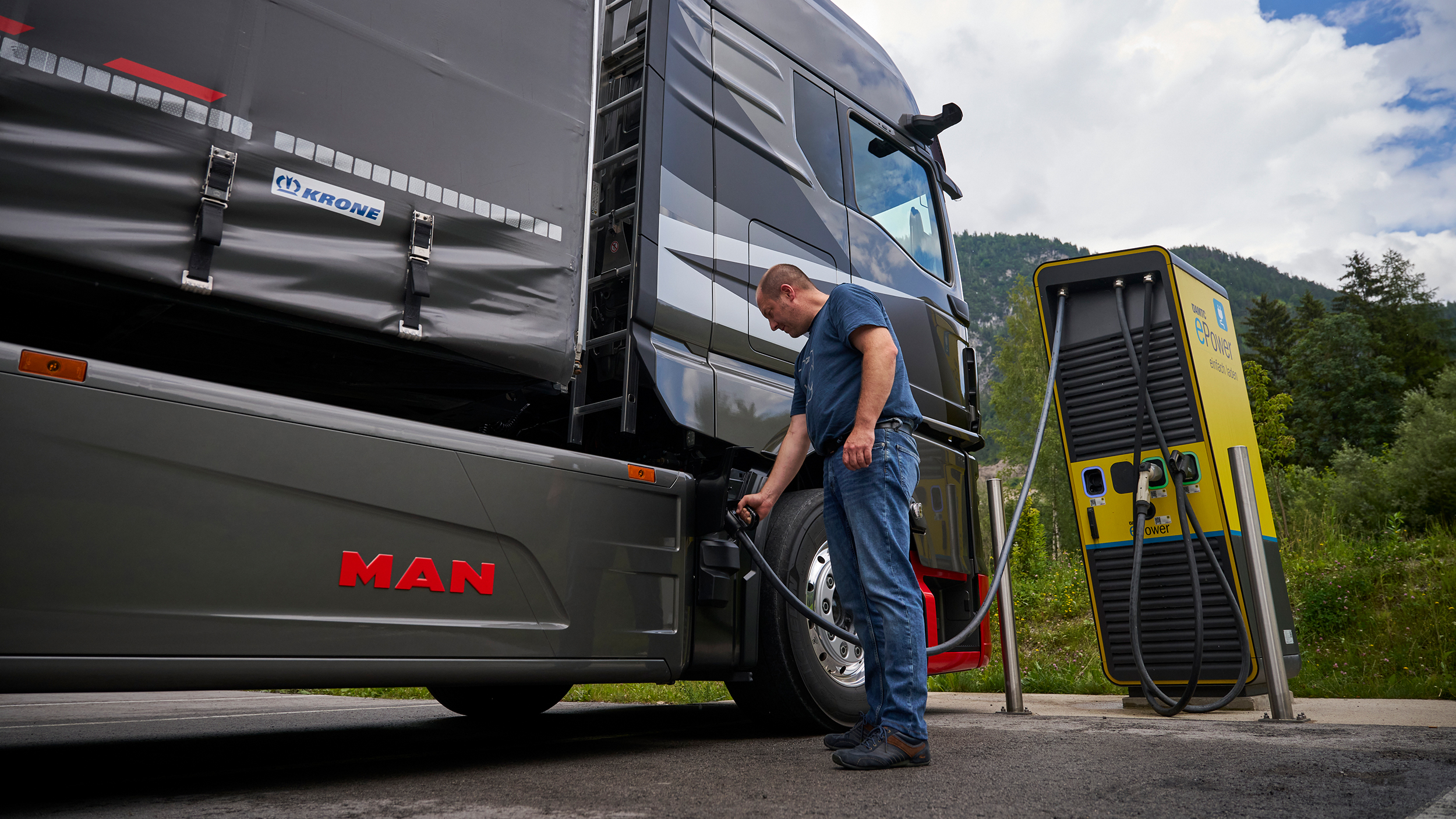 Ein Mann steckt einen Lkw an einer Ladesäule an