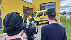Auf dem Bild sieht man zwei Kameraleute von hinten, die gerade einen ÖAMTC-Pannenfahrer interviewen. Im Hintergrund steht ein Fahrzeug des ÖAMTC.