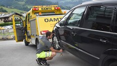 Das Bild zeigt Pannenfahrer Daivd, wie er neben einem schwarzen Auto kniet und einen Gurt festmacht, um dieses Auto mit dem Pannenfahrzeug abzuschleppen.