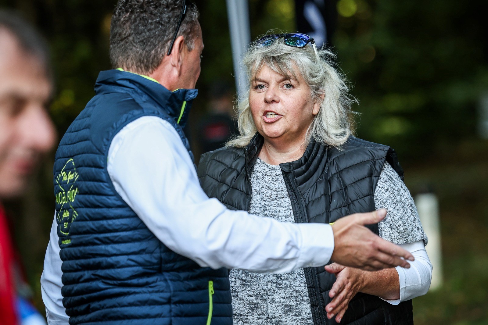 Auf dem Bild sieht man eine Frau im Gespräch mit einem Mann. Den Mann sieht man nur von hinten, die Frau von vorne.