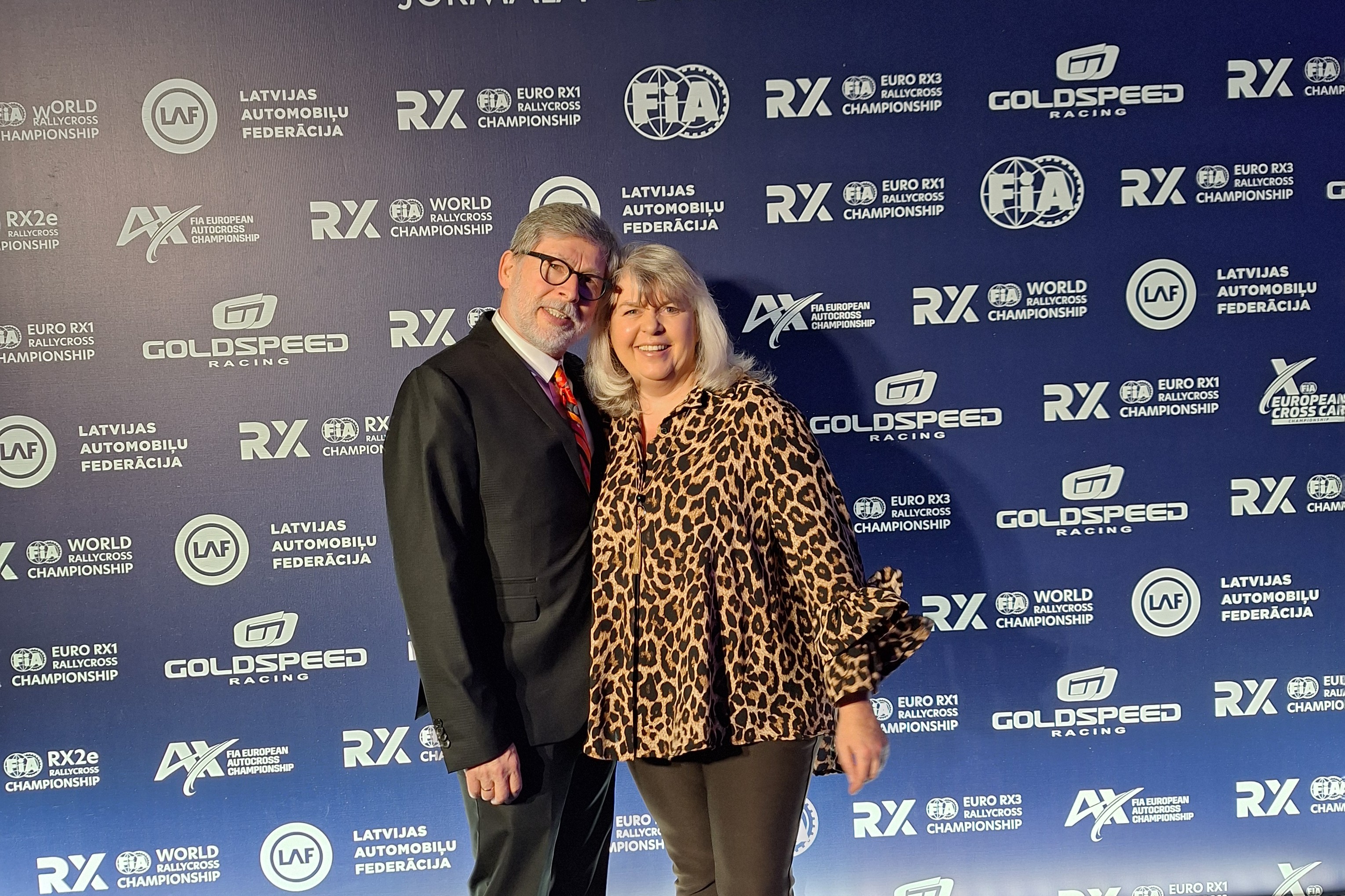 Auf dem Bild sieht man eine Frau und einen Mann vor einer blauen Wand mit unterschiedlichen Schriftzügen.