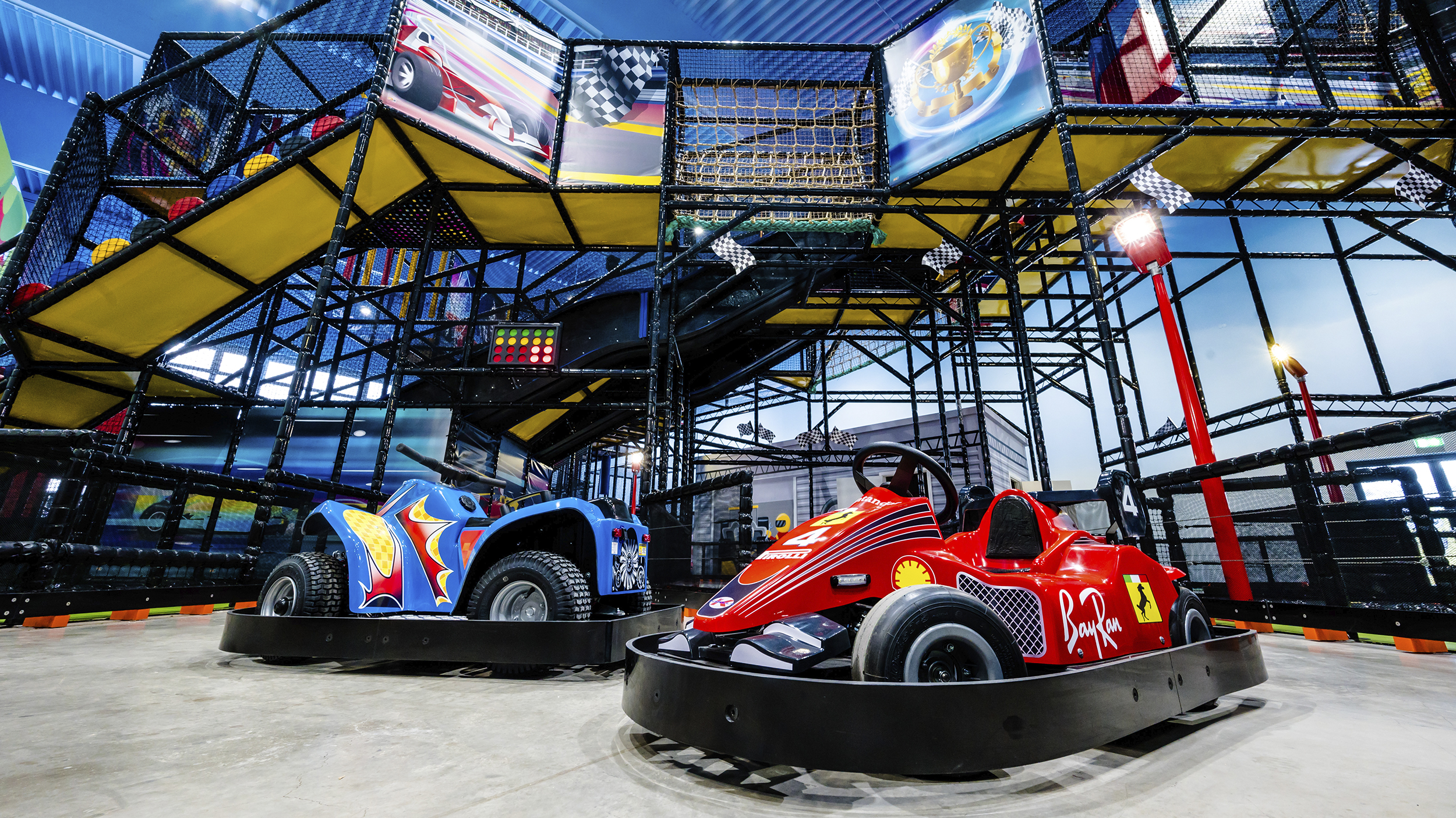 Rennautos und Klettergerüste im Hintergrund auf Indoor-Spielplatz.