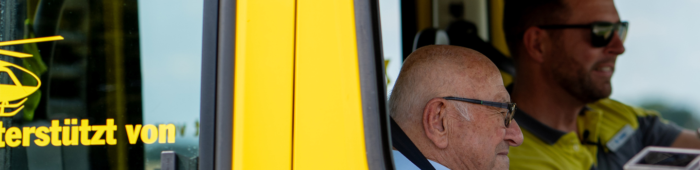 Auf dem Bild sieht man einen kleinen Ausschnitt, Durch ein offenes Autofenster wurden ein alter und ein junger Mann fotografiert.