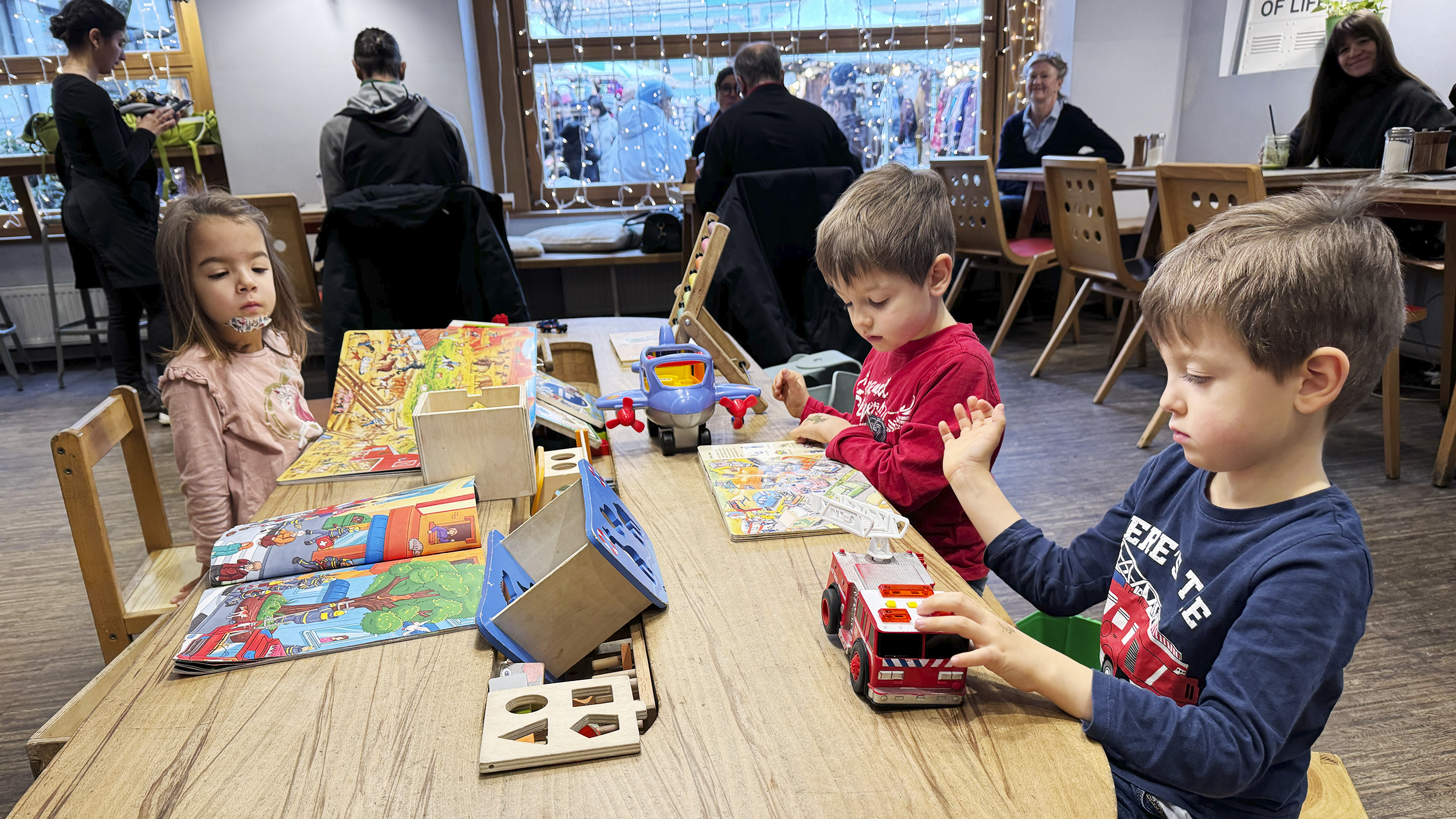 drei Kinder spielen auf einem Tisch im Café