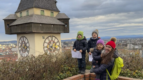 Redakteurin Conny mit ihren Drillingen am Schlossberg in Graz neben dem Uhrturm.