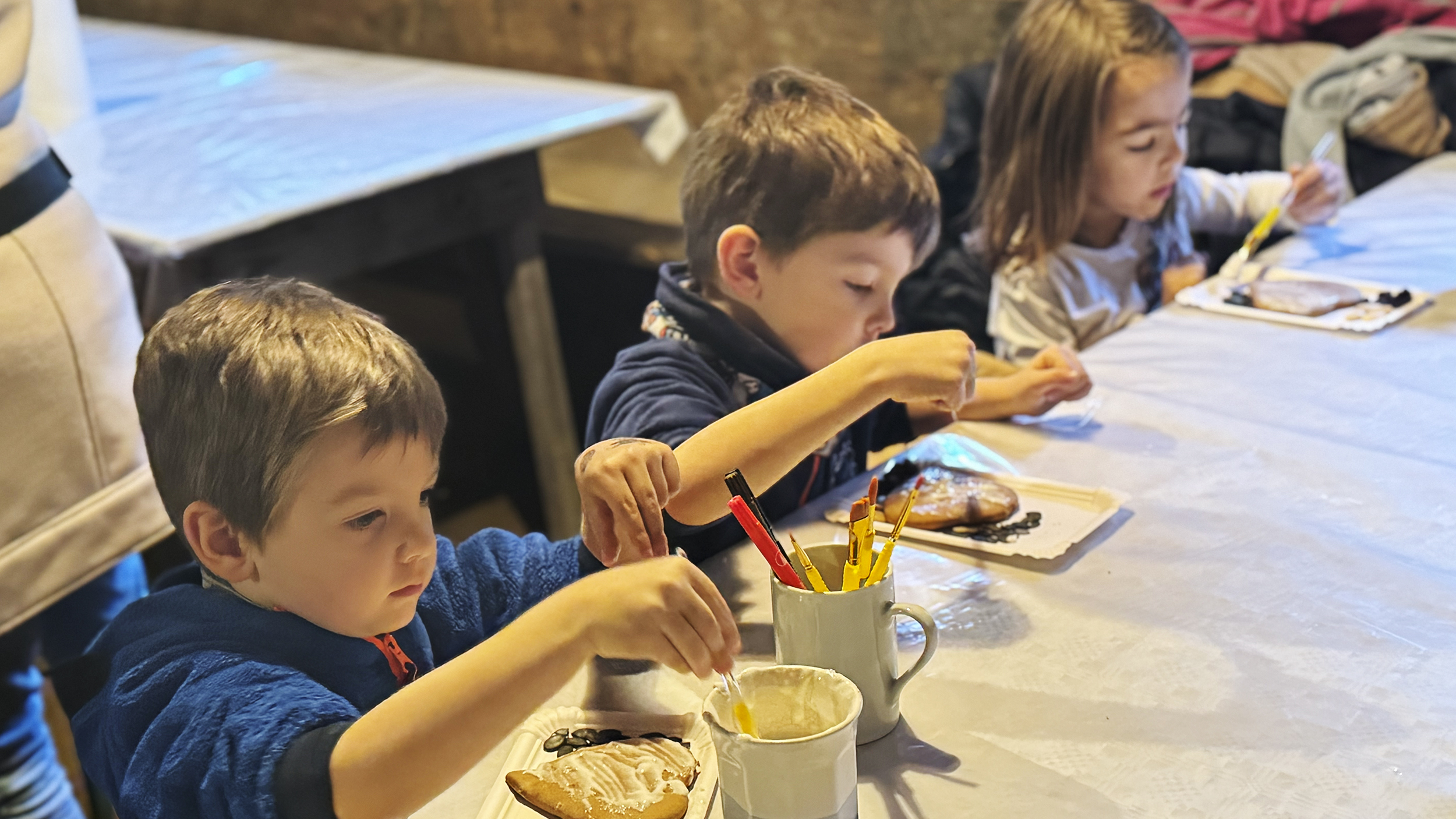 Drei Kinder verzieren ihren Lebkuchen.