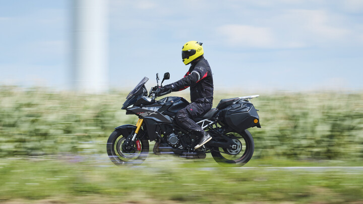 Grauer Sporttourer fahrend seitlich fotografiert.