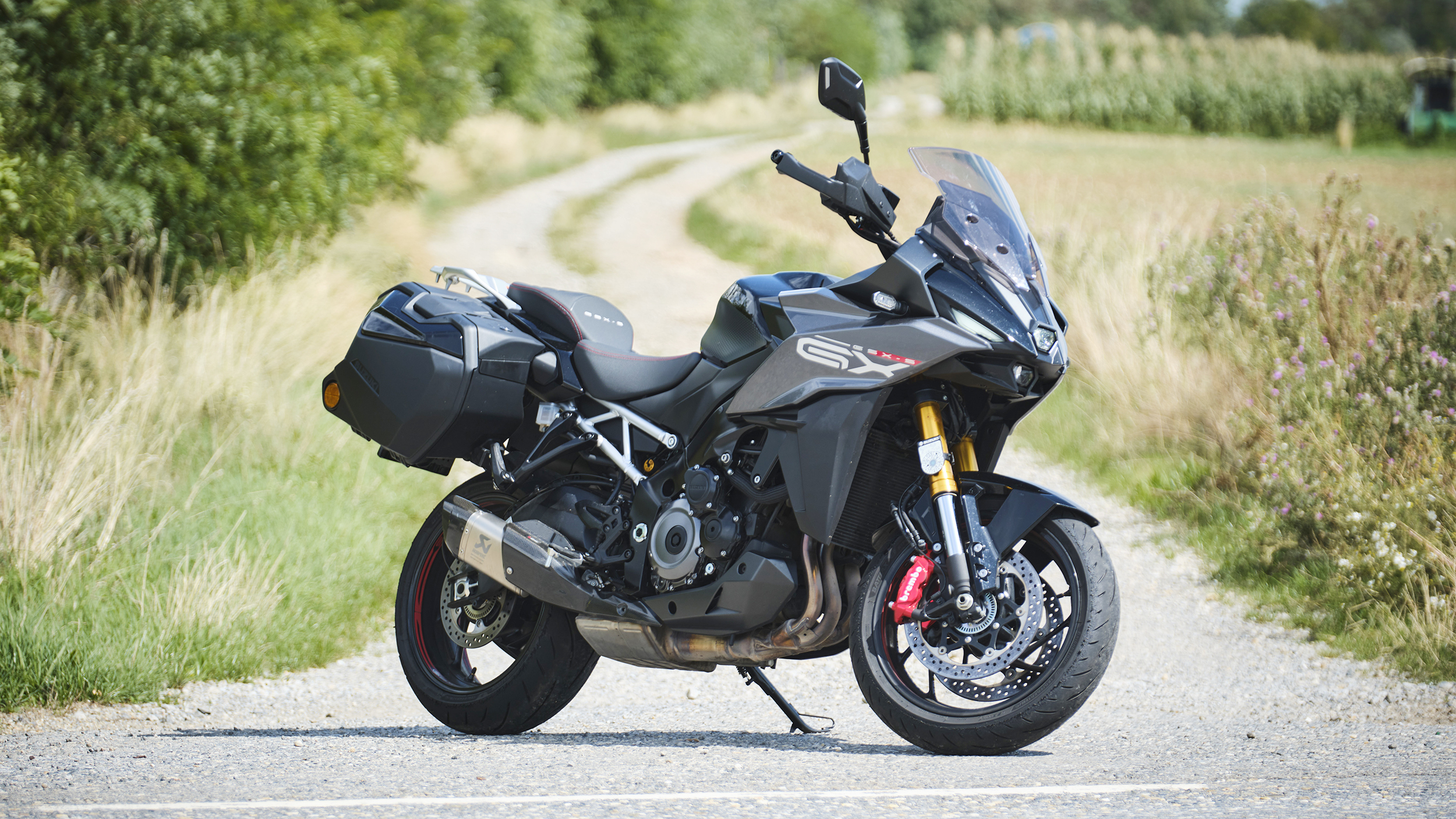 Grauer Sporttourer mit zwei montierten Koffern von schräg vorne fotografiert.