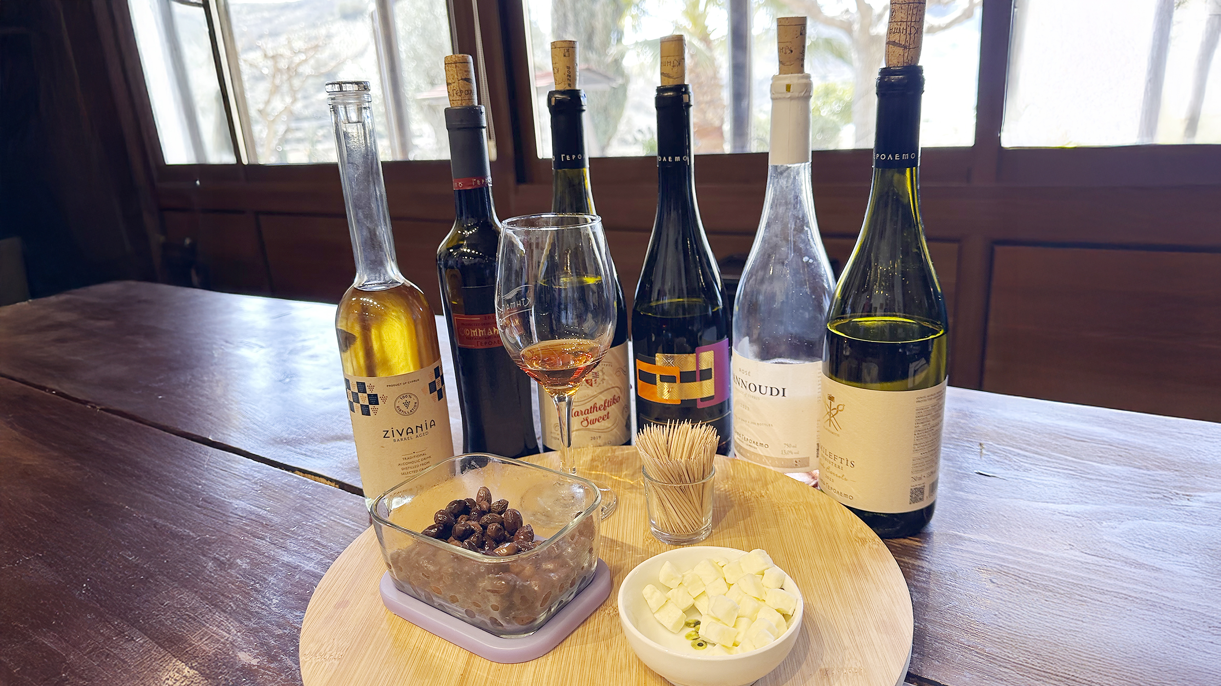 Mehere Weinflaschen stehen auf einem Tisch, davor Käse und Oliven zum Verkosten.