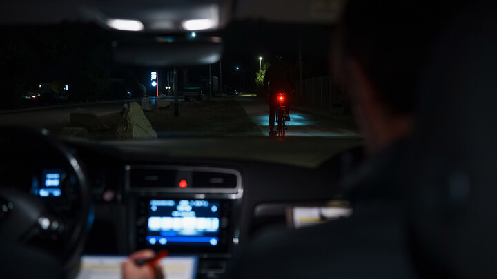 Ein Fahrrad, fotografiert aus einem fahrenden Auto, fährt in der Nacht.