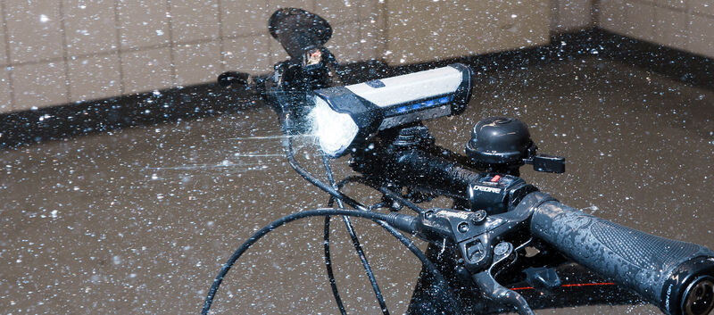 Ein Fahrrad steht in einem Labor im künstlichen Regen mit aktivierter Beleuchtung.