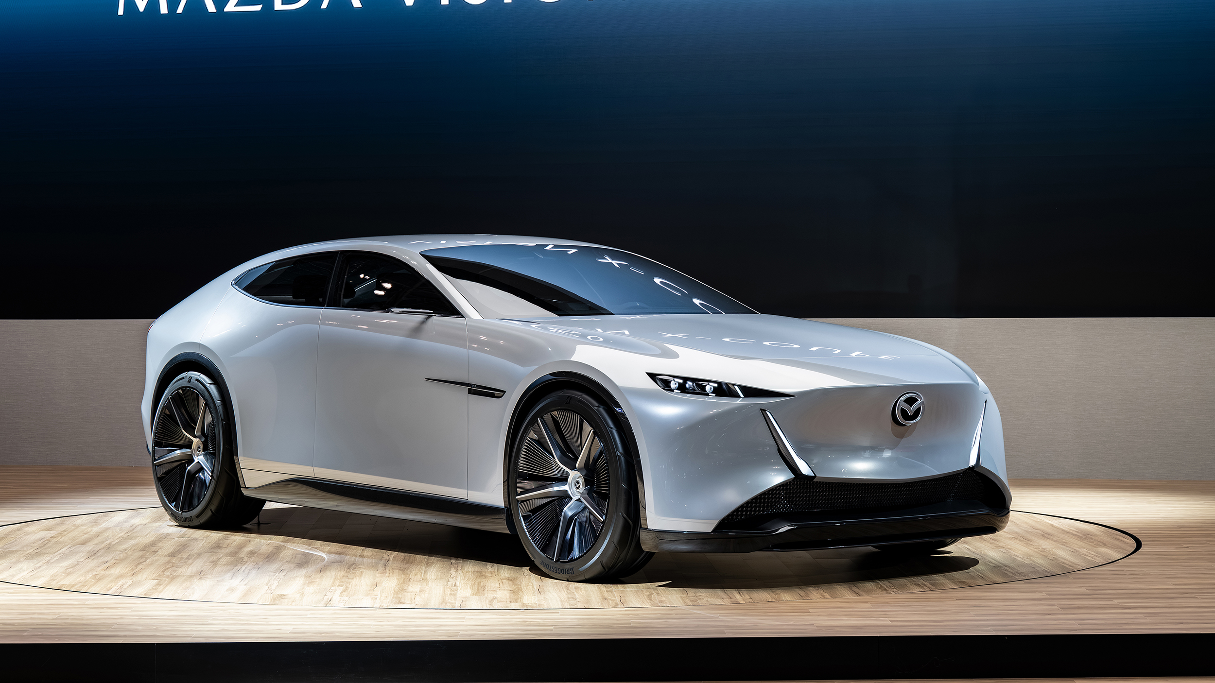 Eine silberne Limousine von Mazda steht auf einer Bühne