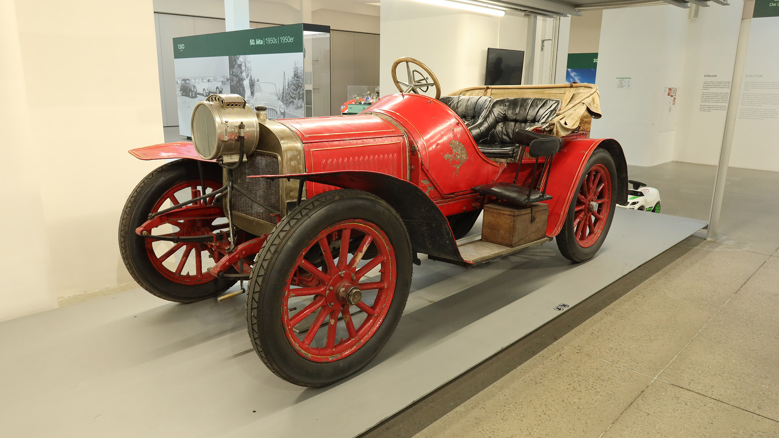 Ein rotes offenes Auto mit hölzernen Speichenrädern.
