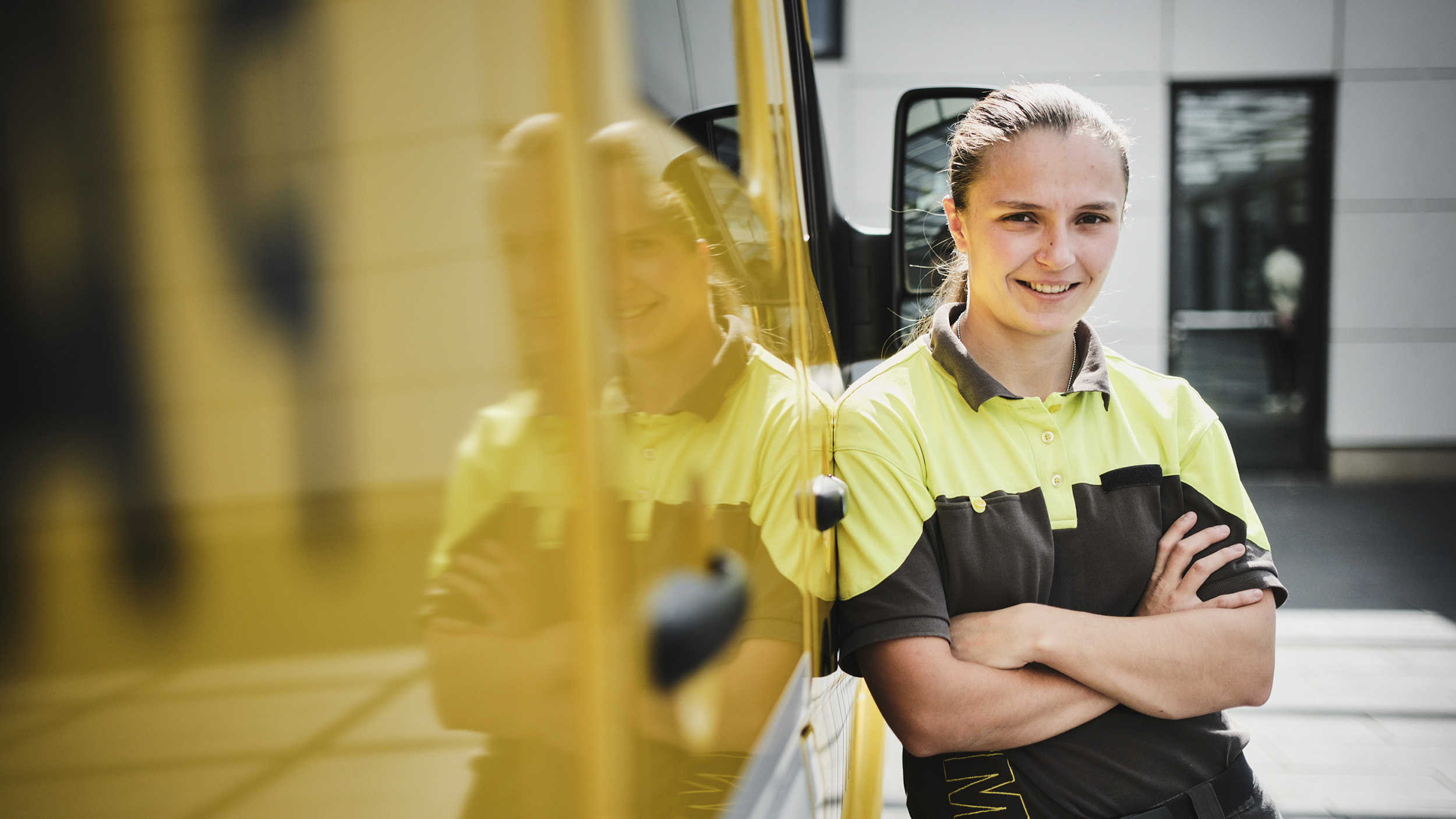 Pannenhelferin Lenie Tieber steht mit verschränkten Händen neben einem großen gelben Fahrzeug.