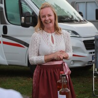 Das Foto zeigt Maria Schwarz, sie trägt ein Dirndl, im Hintergrund ist ein Campingfahrzeug zu sehen.