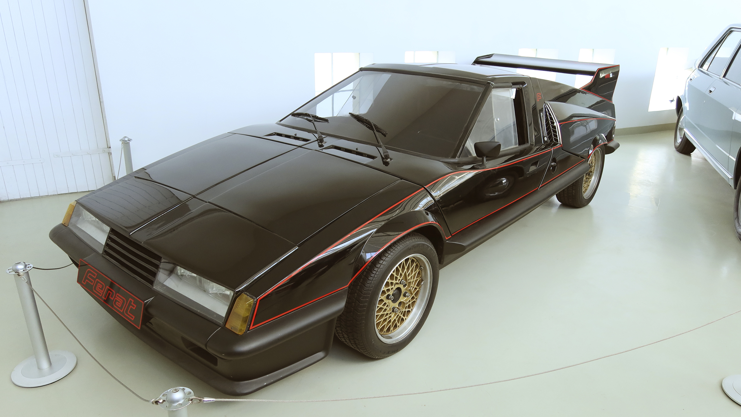 Ein futuristisch aussehendes, flaches schwarzes Sportauto mit Heckspoiler.