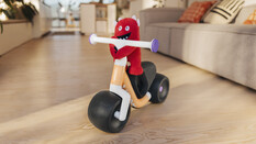 Imagebild des neuen Woom Wow Laufrads mit kleinem roten Stoffmonster am Lenker, im Hintergrund ein Wohnzimmer.