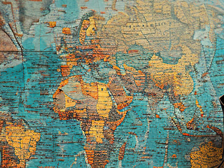 Auf dem Bild sieht man eine Weltkarte, davor steht ein Rucksack.