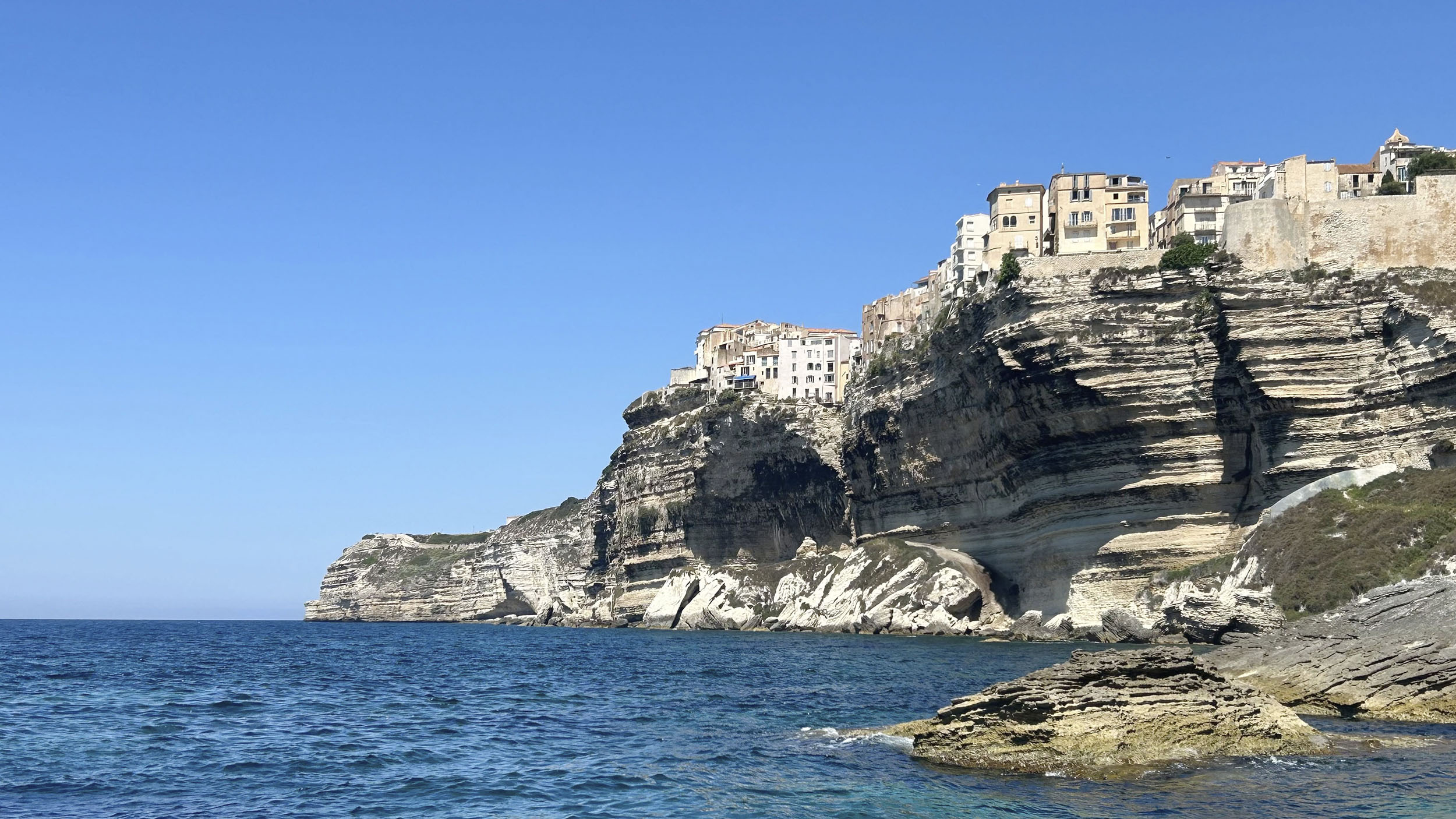 Imposante Felsen am Meer und oben thront eine kleine Stadt. 