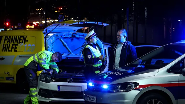 Polizistin klärt Autofahrenden über die Wichtigkeit einer ausreichenden Beleuchtung auf. Im Hintergrund wird von einem ÖAMTC-Techniker die Lampe beim Auto getauscht. Die gemeinsame Aktion nennt sich Licht statt Strafe.