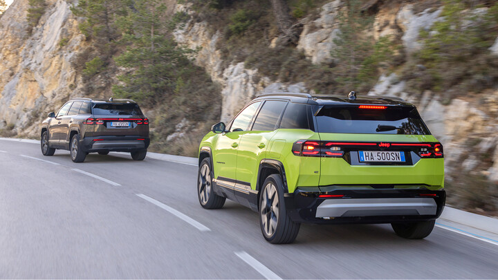 Ein grauer und ein grüner Jeep Compass fahren auf einer Landstraße an einer Felswand vorbei.