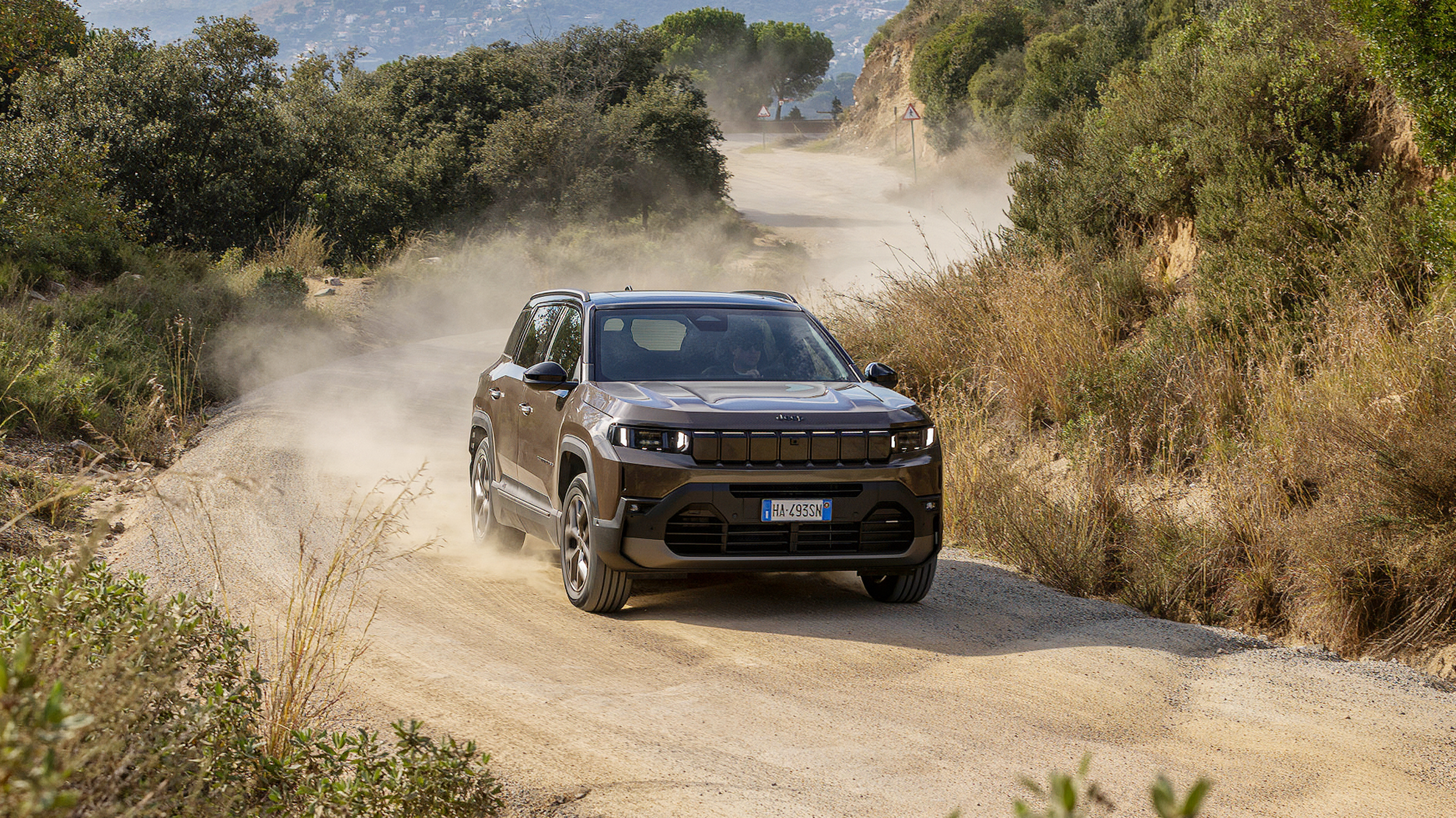 Ein grauer Jeep Compass fährt über eine unbefestigte Schotterstraße.