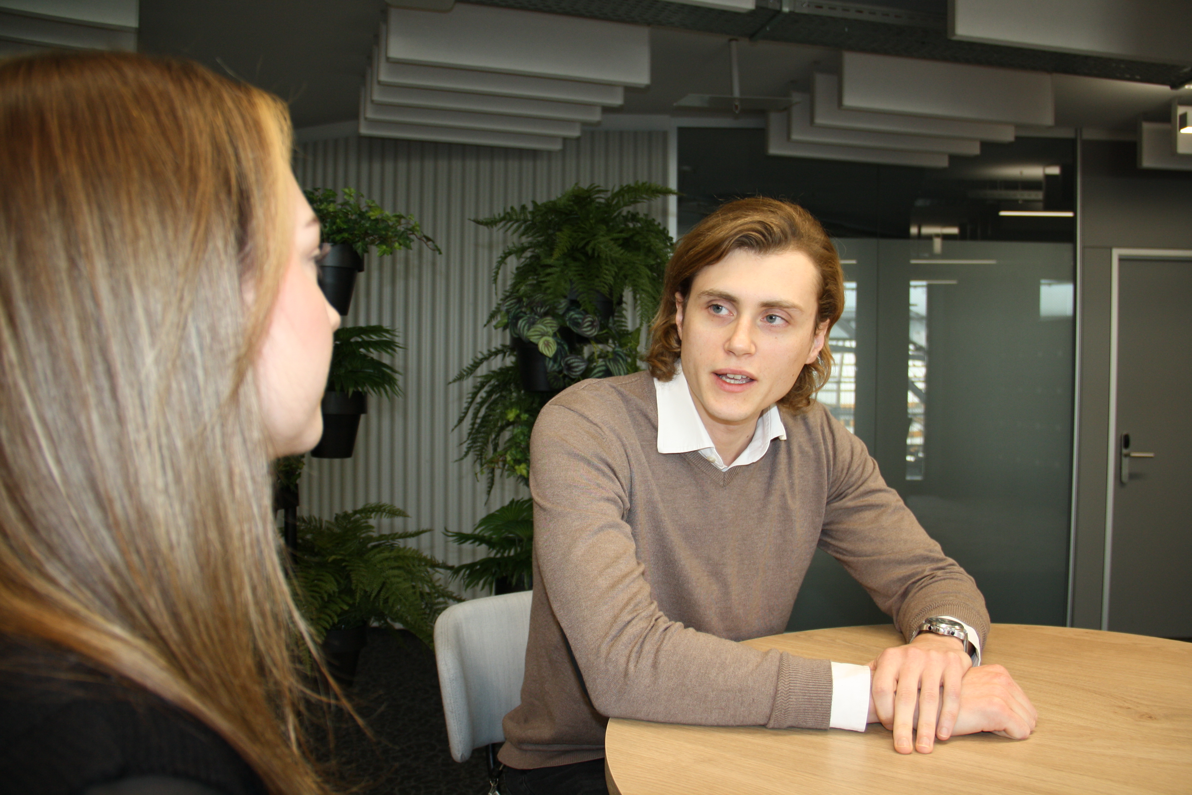 Ein Mann und eine Frau sitzen einander an einem Tisch gegenüber und führen ein Interview. Der Mann spricht, während die Frau ihm aufmerksam zuhört.