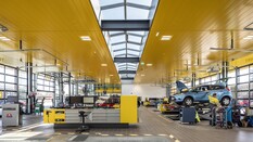 Das Bild zeigt die Prüfhalle in St. Pölten von innen. auf der linken Seite ist eine Werkbank, rechts wird gerade ein blaues Auto von einem Mitarbeiter kontrolliert.