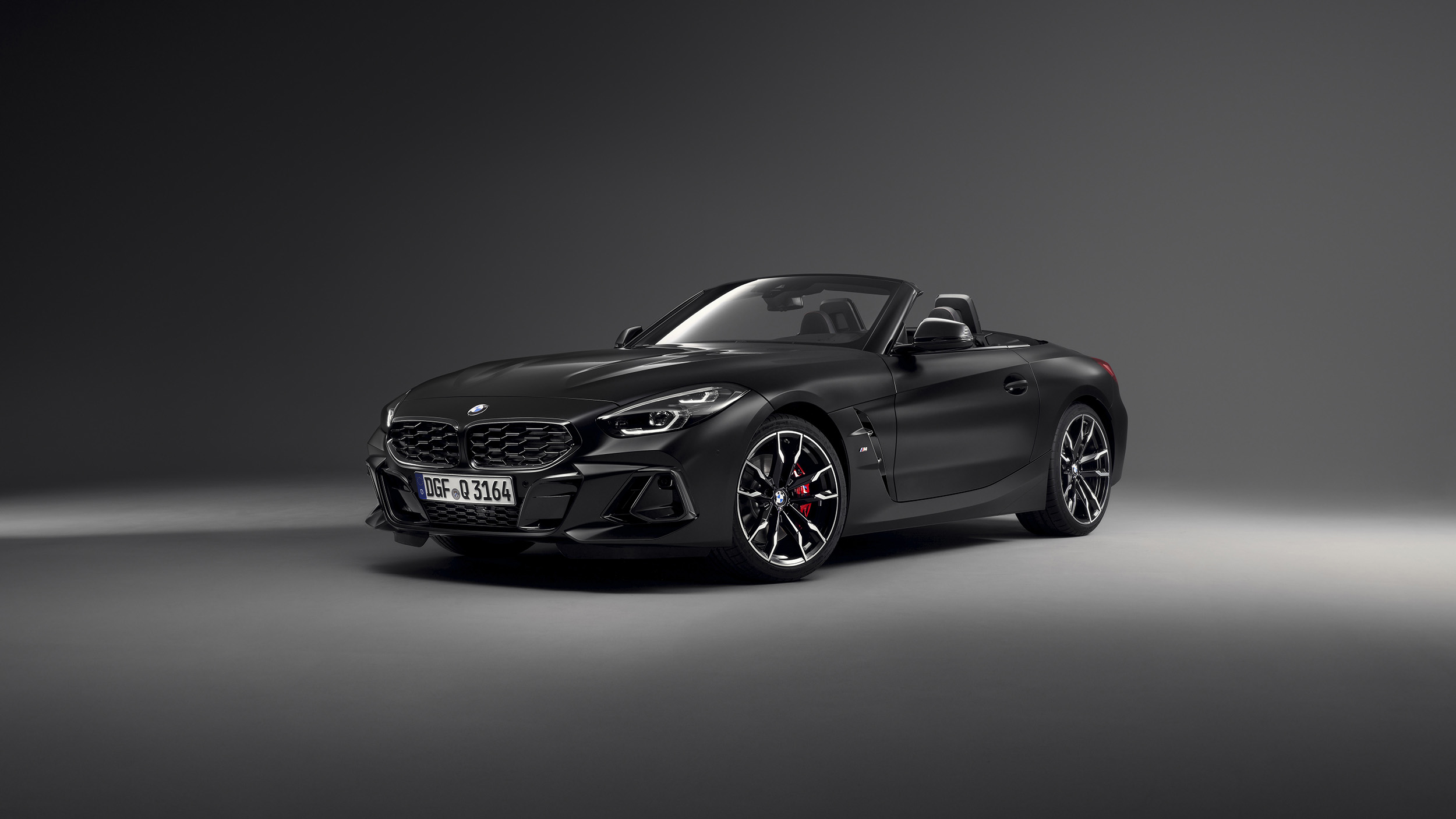 Ein mattschwarzes BMW Z4 Cabrio steht in einem dunklen Studio, von schräg vorne