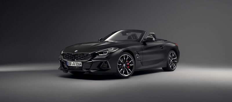 Ein mattschwarzes BMW Z4 Cabrio steht in einem dunklen Studio, von schräg vorne