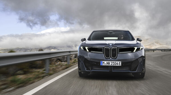 Ein dunkelgrauer BMW iX3 fährt auf einer Landstraße.