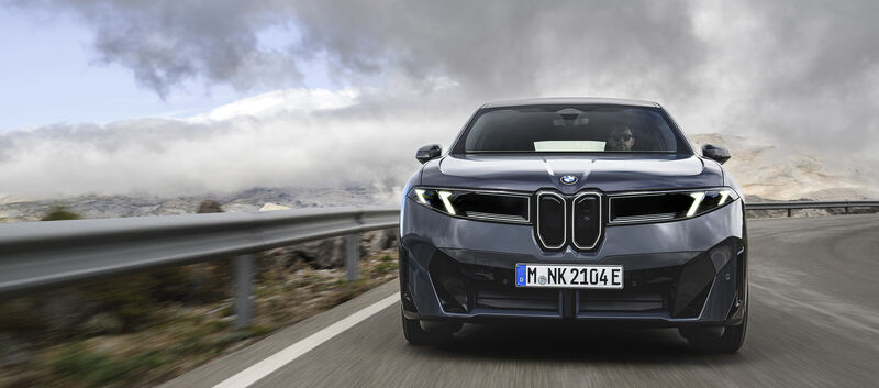 Ein dunkelgrauer BMW iX3 fährt auf einer Landstraße.