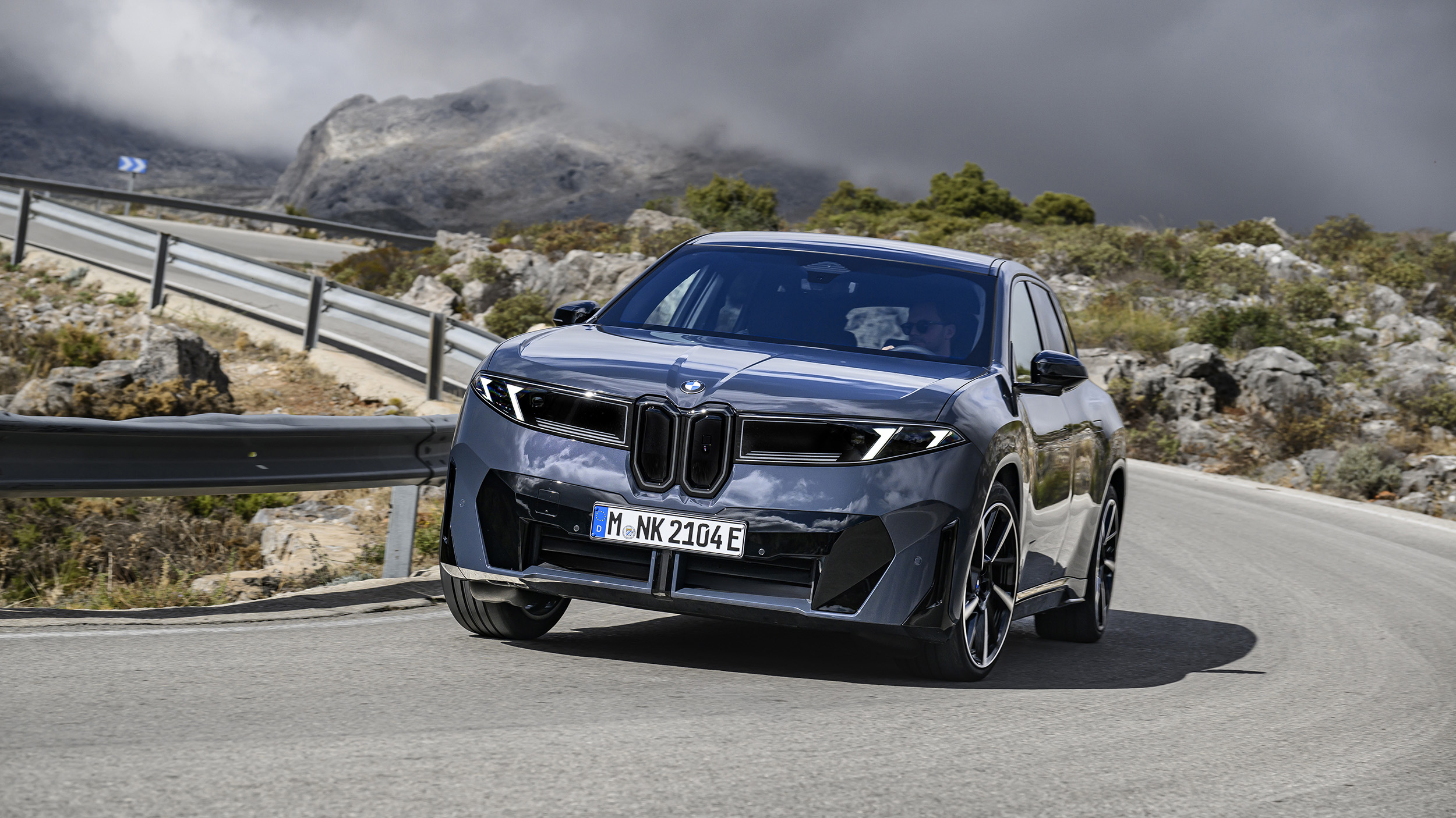 Ein dunkelgrauer BMW fährt durch eine Kurve auf einer Landstraße.