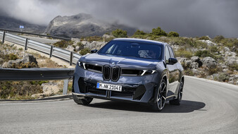 Ein dunkelgrauer BMW fährt durch eine Kurve auf einer Landstraße.