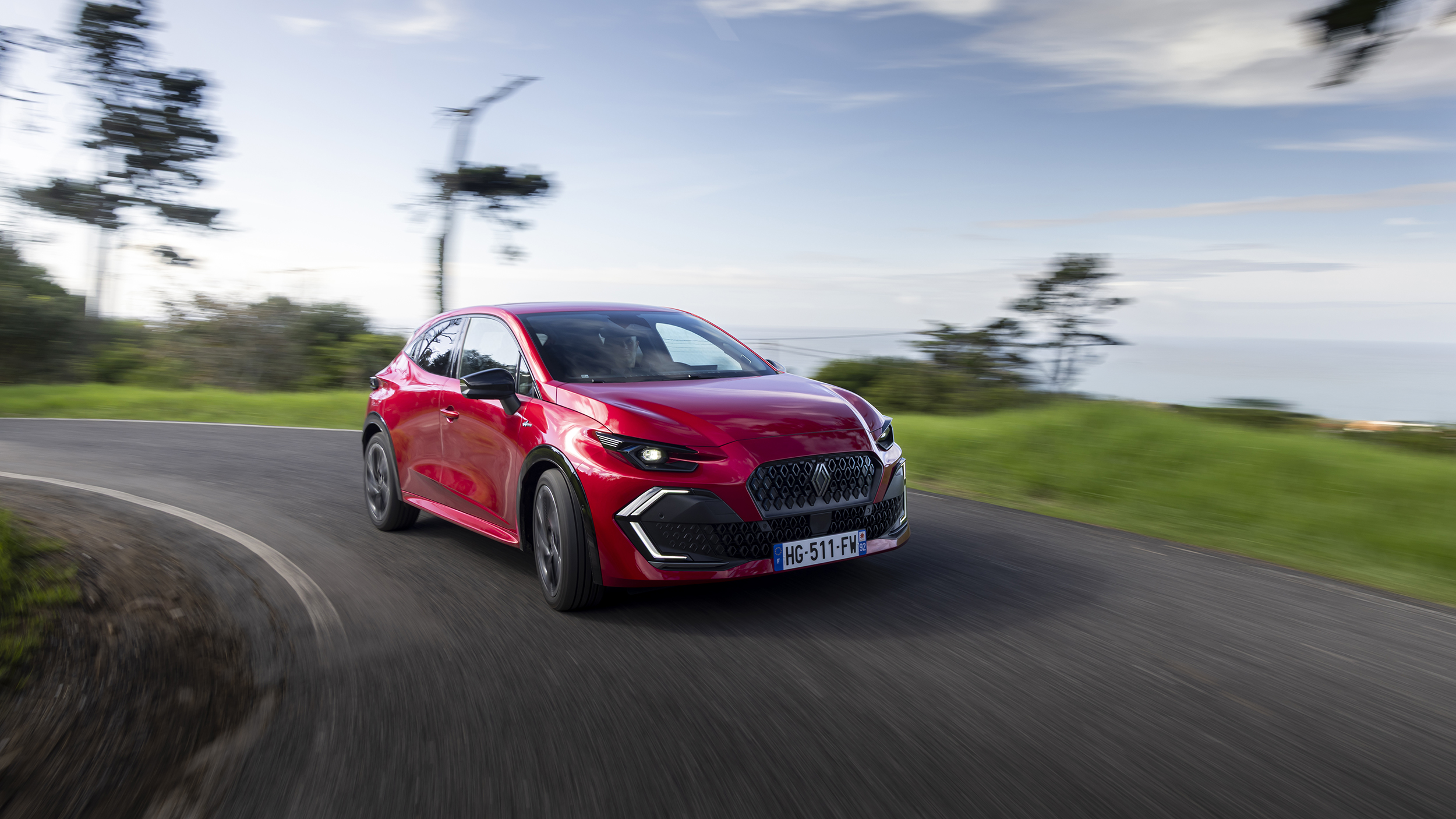 Ein roter Renault Clio fährt um die Kurve.